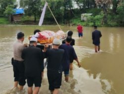 Tak Peduli Derasnya Arus Sungai, Bhabinkamtibmas Ini Tetap Usung Jenazah Ke Pemakaman